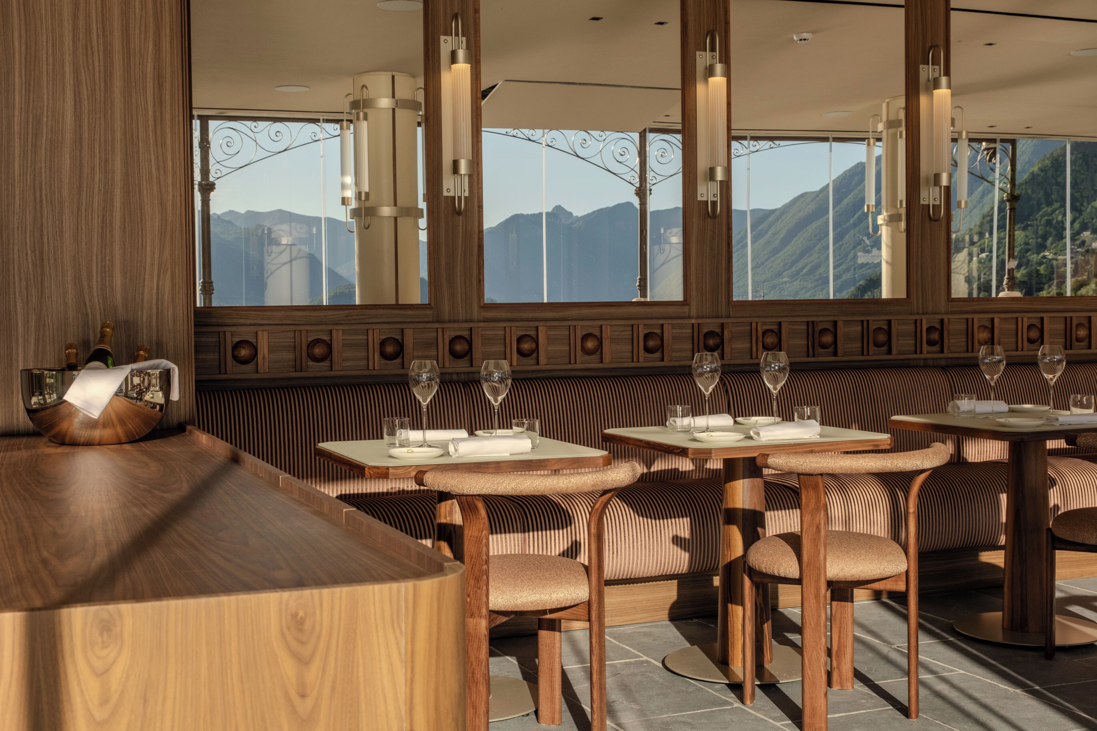 Un restaurante con muebles de madera, ventanas amplias y vistas a las montañas.