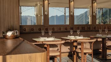 Un restaurante con muebles de madera, ventanas amplias y vistas a las montañas.
