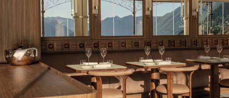 Un restaurante con muebles de madera, ventanas amplias y vistas a las montañas.