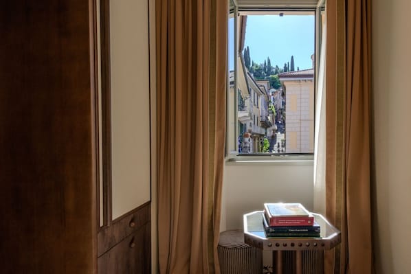 A room with a window, curtains, a radiator, and a small table with books.