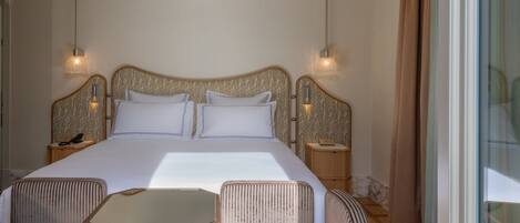 Une chambre d’hôtel avec un grand lit, deux tables de chevet, une petite table avec des chaises et une grande fenêtre.