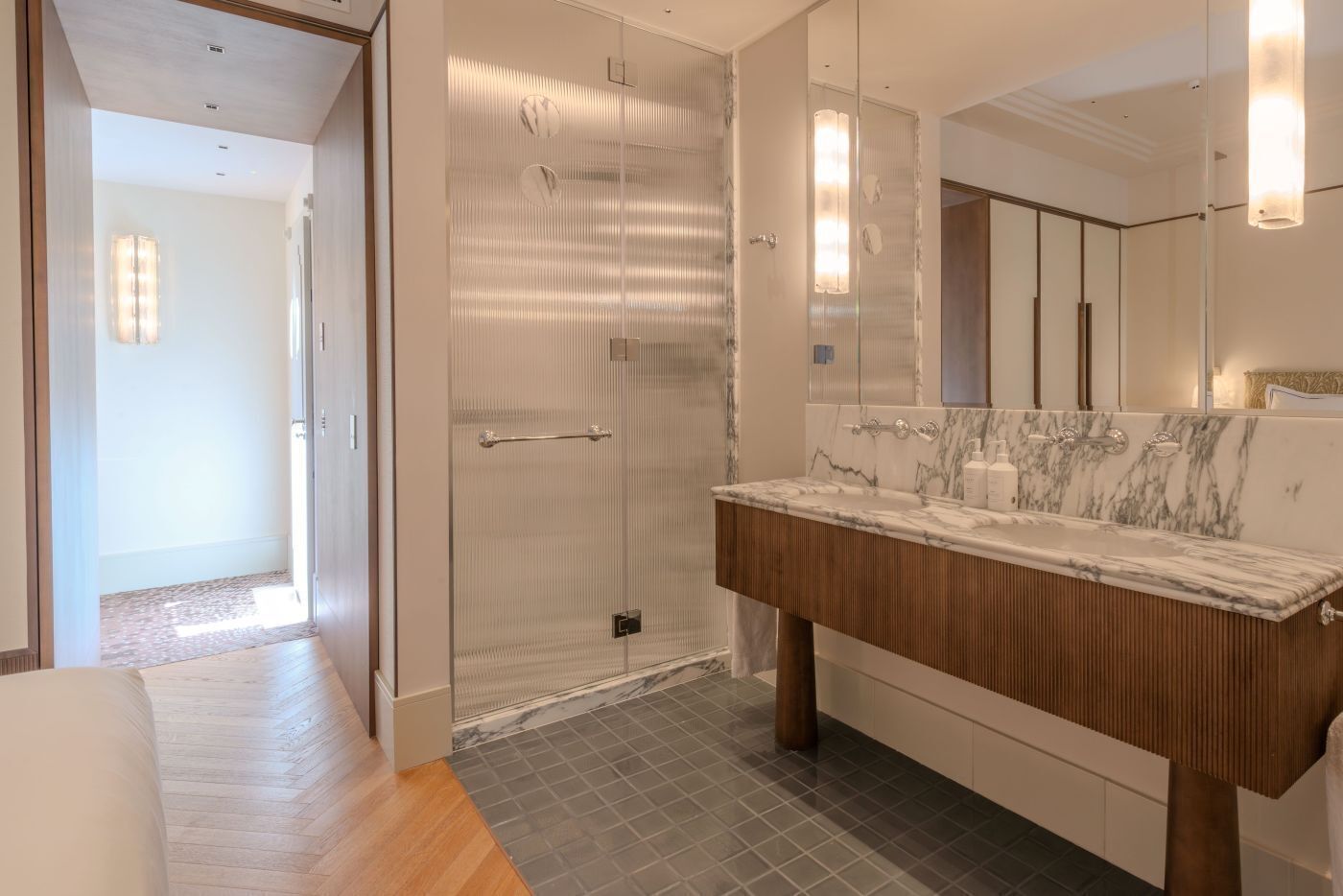 Un baño moderno con cabina de ducha de vidrio, lavabo de mármol y un espejo grande.