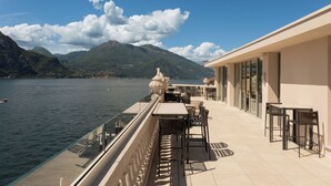 A terrace with tables and chairs overlooking a body of water and mountains. - Palazzo Genazzini (Bellagio)