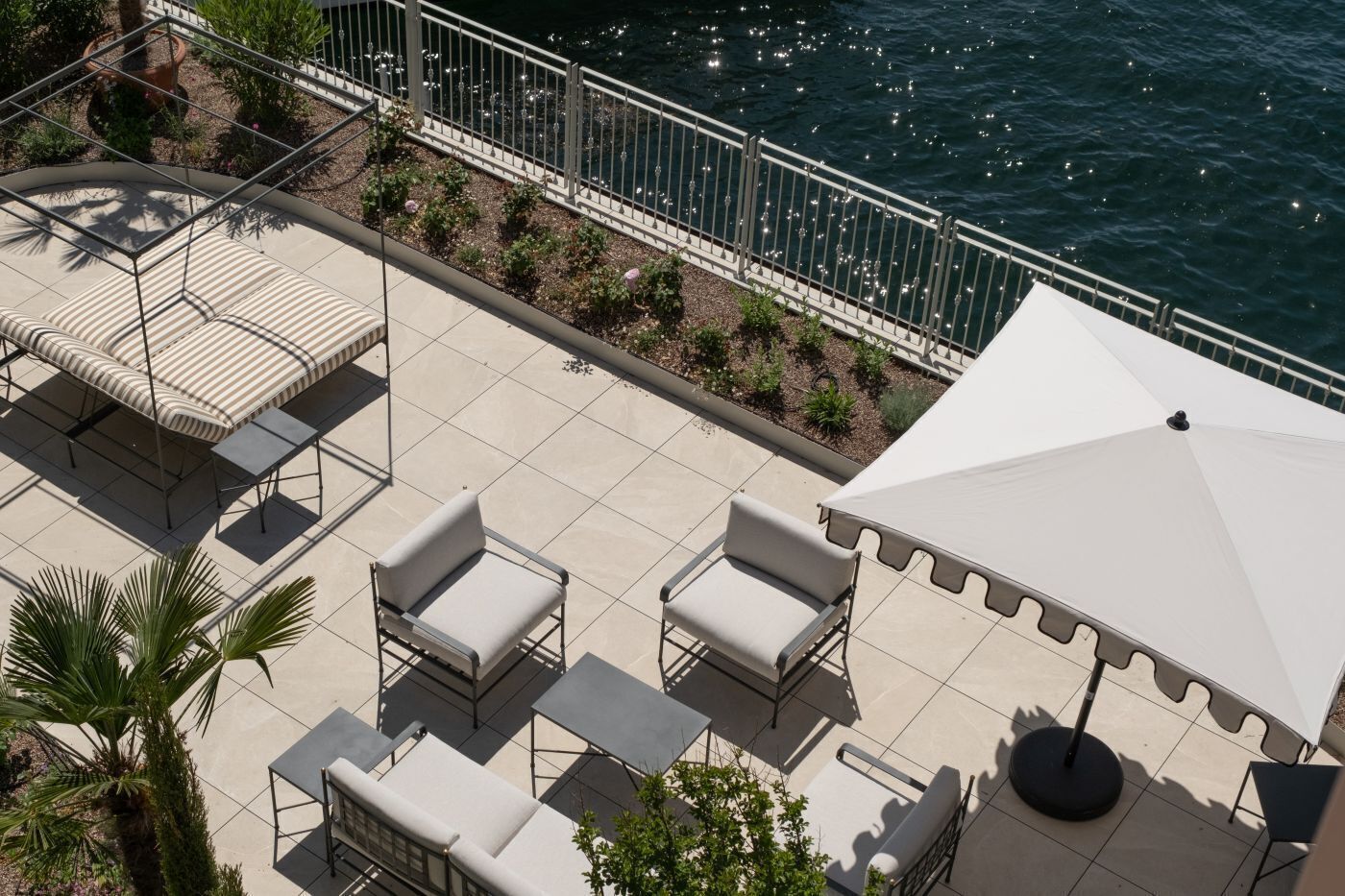 An outdoor patio with a white umbrella, cushioned chairs, and a small table.