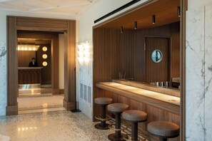 A modern bathroom with a wooden vanity, a mirror, and three stools.