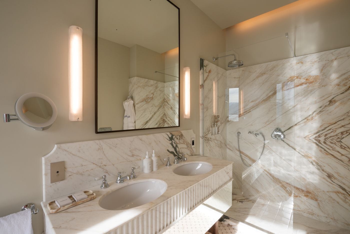 A bathroom with two sinks, a large mirror, and a shower with a glass door.