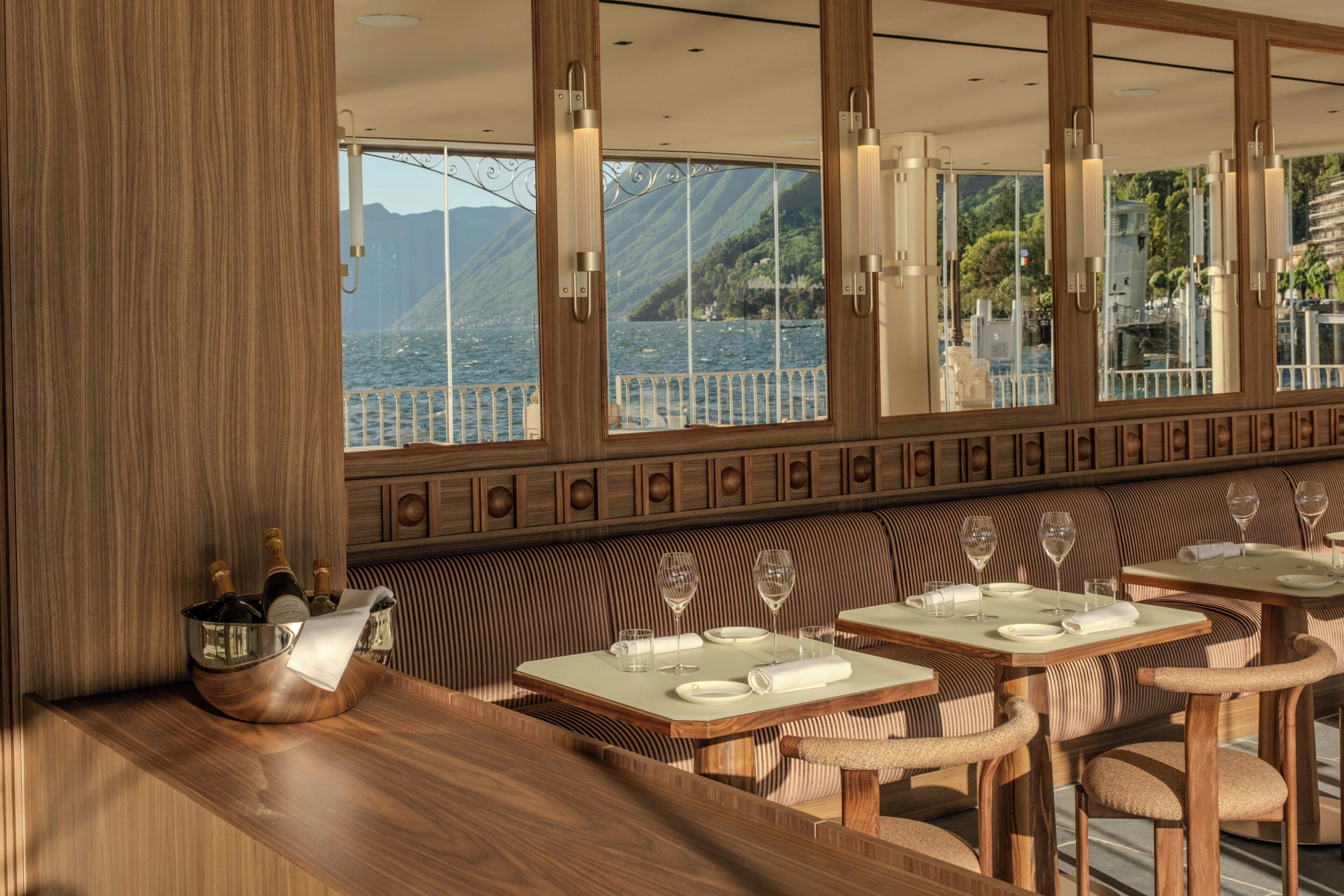 Ein Restaurant mit Holzmöbeln, großen Fenstern und Meerblick.