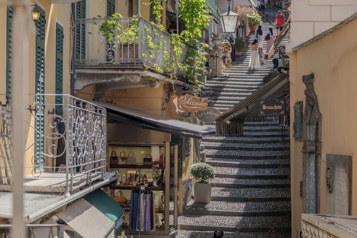 A narrow street with a shop named 'Rondino' at the bottom, a staircase leading to a higher level, and a sign for 'Bruschini' above the stairs.