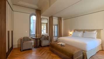 Une chambre d’hôtel avec un grand lit, deux fauteuils, une petite table et une armoire.