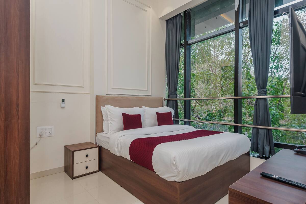 Une chambre à coucher moderne avec un lit en bois, une literie blanche, une table de chevet et une grande fenêtre avec des rideaux.