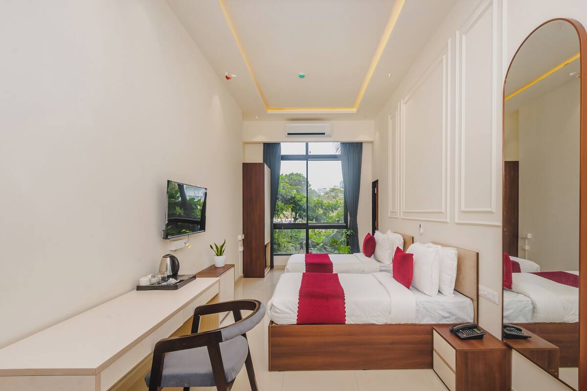 Une chambre d’hôtel comprenant un lit, un bureau, une chaise, une télévision, une fenêtre donnant sur un paysage agréable et un miroir.