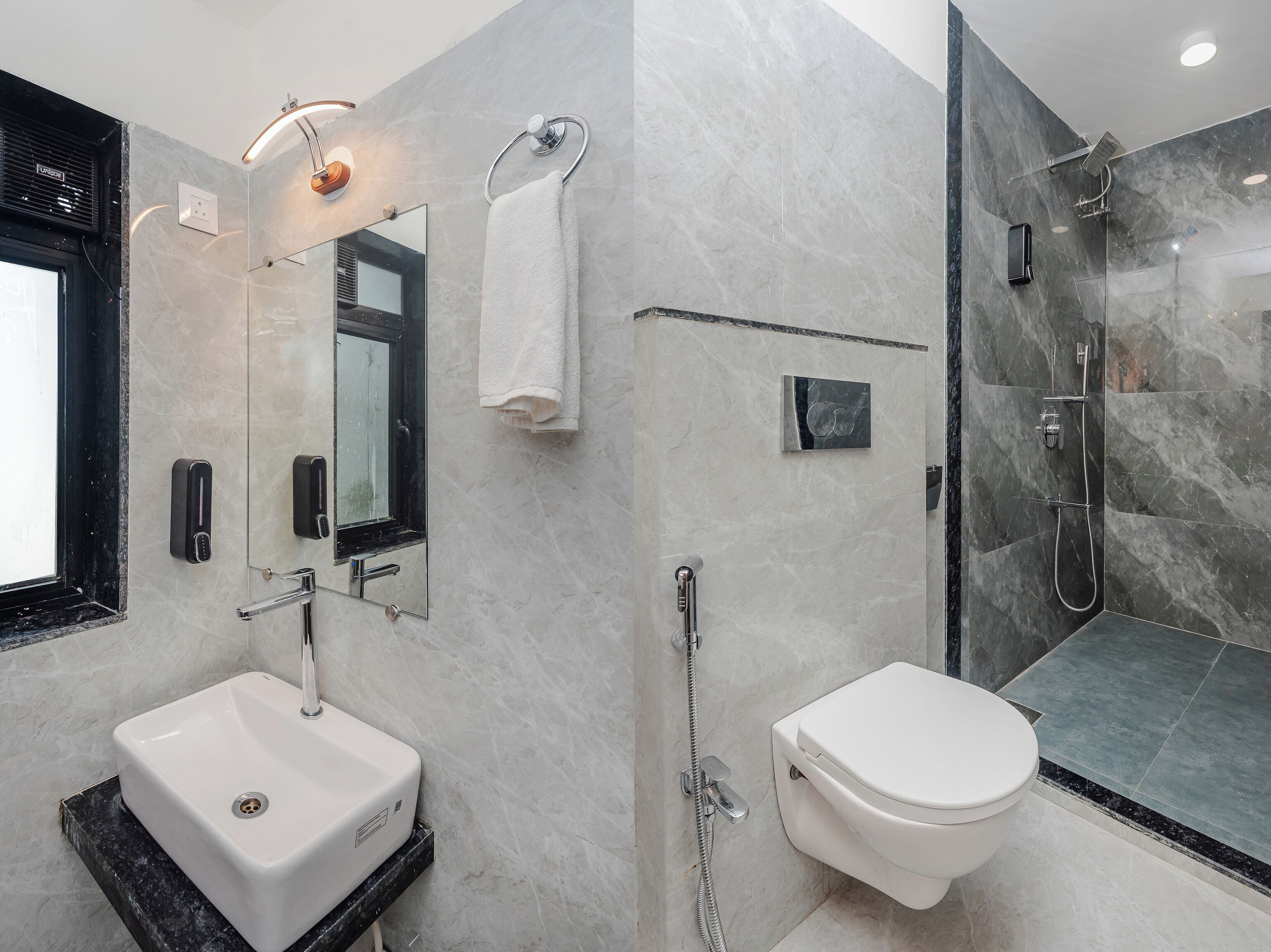 A modern bathroom with a sink, mirror, towel rack, toilet, and shower.