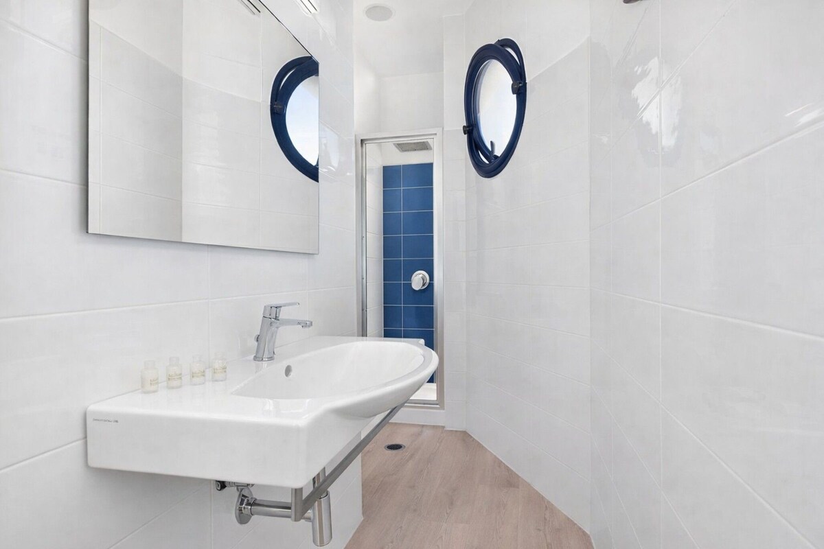 A bathroom with a white sink, a mirror, and a blue shower enclosure.