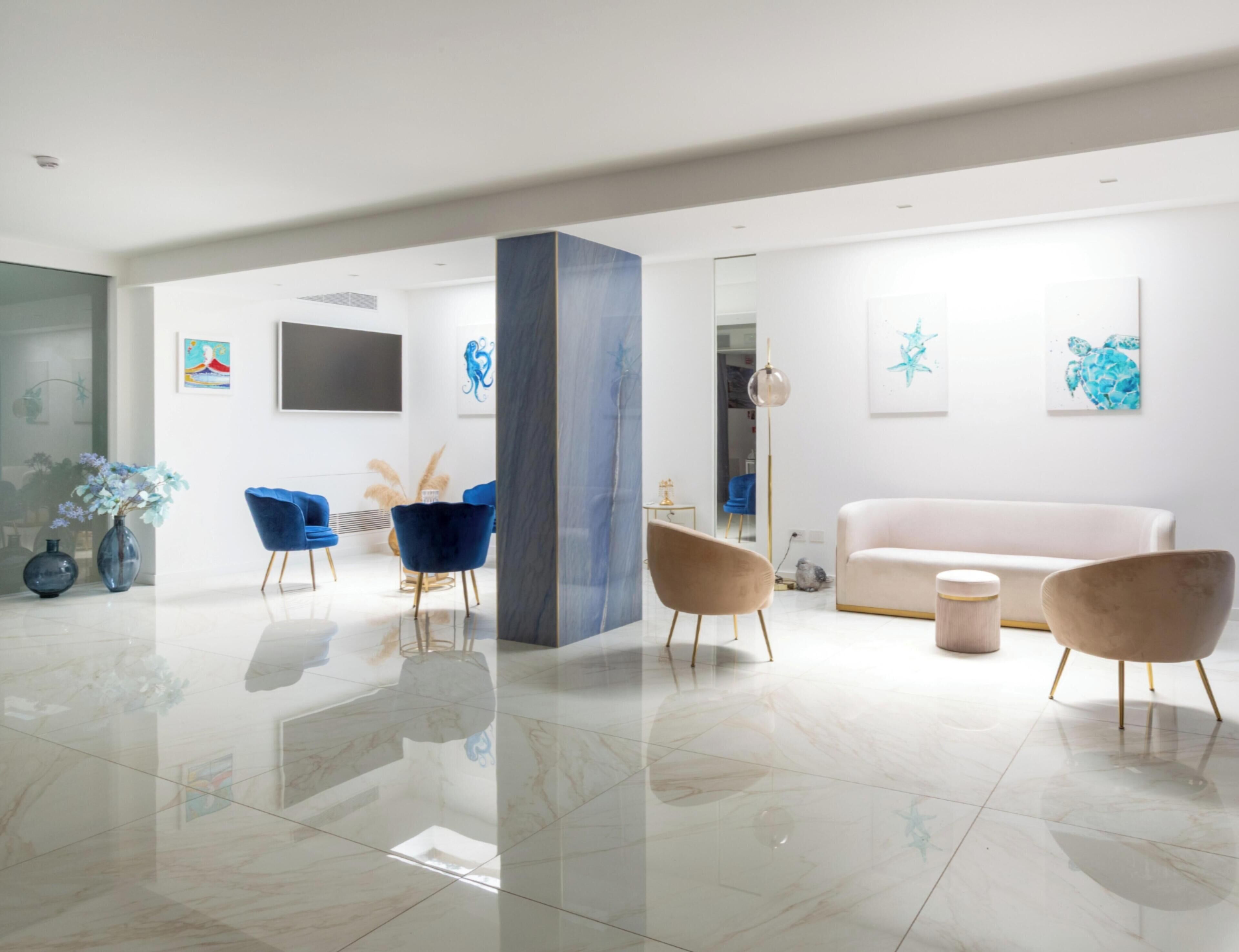 A modern living room with a large column, a white sofa, and blue chairs.