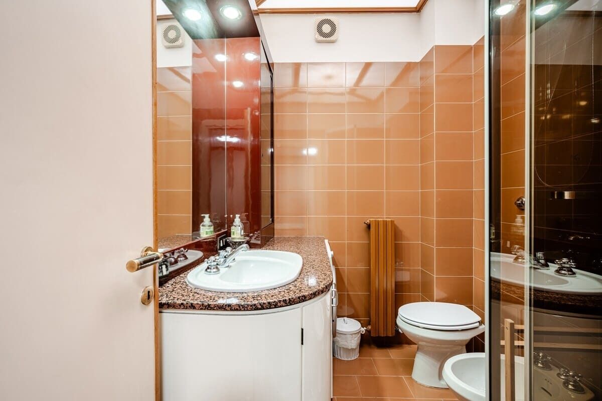 A bathroom with a white sink, a mirror, and a toilet.