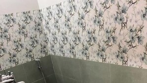 A bathroom with a toilet, a shower, and a bucket.