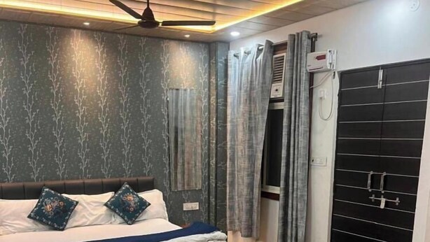 A bedroom with two beds, a ceiling fan, and a black wardrobe.