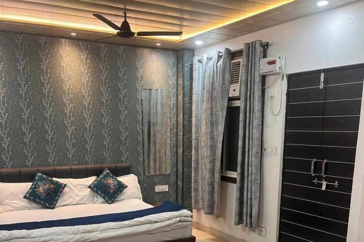Un dormitorio con dos camas, ventilador de techo y armario negro.