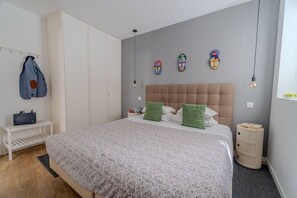 A bedroom with a bed, a wardrobe, a nightstand, and a wall-mounted light fixture. - By the Castle | Cozy & Comfy | Family-Friendly (Lisboa)