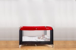 Ein kleines Bett mit einem roten Baldachin, einer weißen Matratze und einem Holzboden.