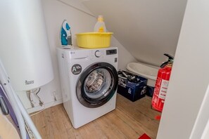 A compact laundry area with a washing machine, a drying rack, and a fire extinguisher. - By the Castle | Cozy & Comfy | Family-Friendly (Lisboa)
