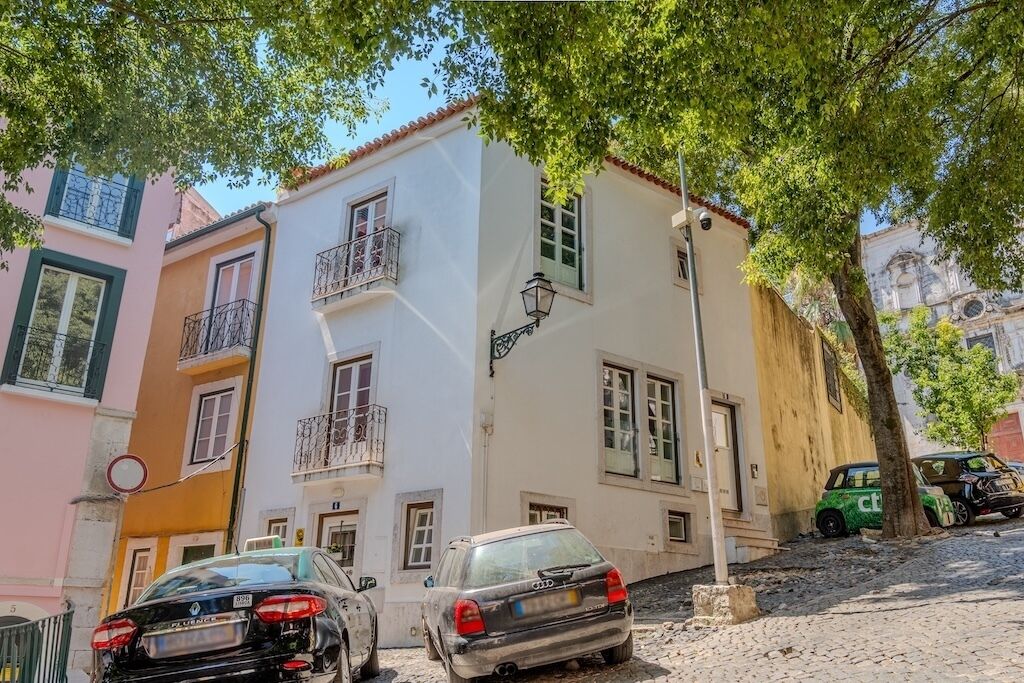 Une rue bordée d’immeubles, avec une voiture et un arbre.