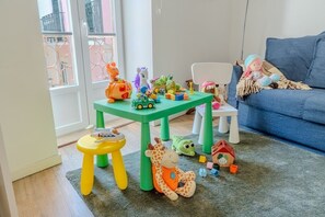 A child's play area with a green table, a yellow stool, and various toys scattered on the floor. - By the Castle | Cozy & Comfy | Family-Friendly (Lisboa)