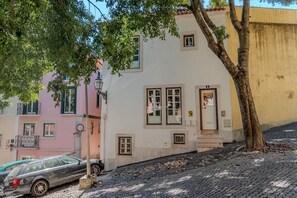 A building with a white facade, multiple windows, and a tree in front. - By the Castle | Cozy & Comfy | Family-Friendly (Lisboa)