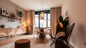 A cozy living room with a dining area, featuring a round table, chairs, and a hanging light fixture. - Luga Homes - Augustusplatz (Leipzig)