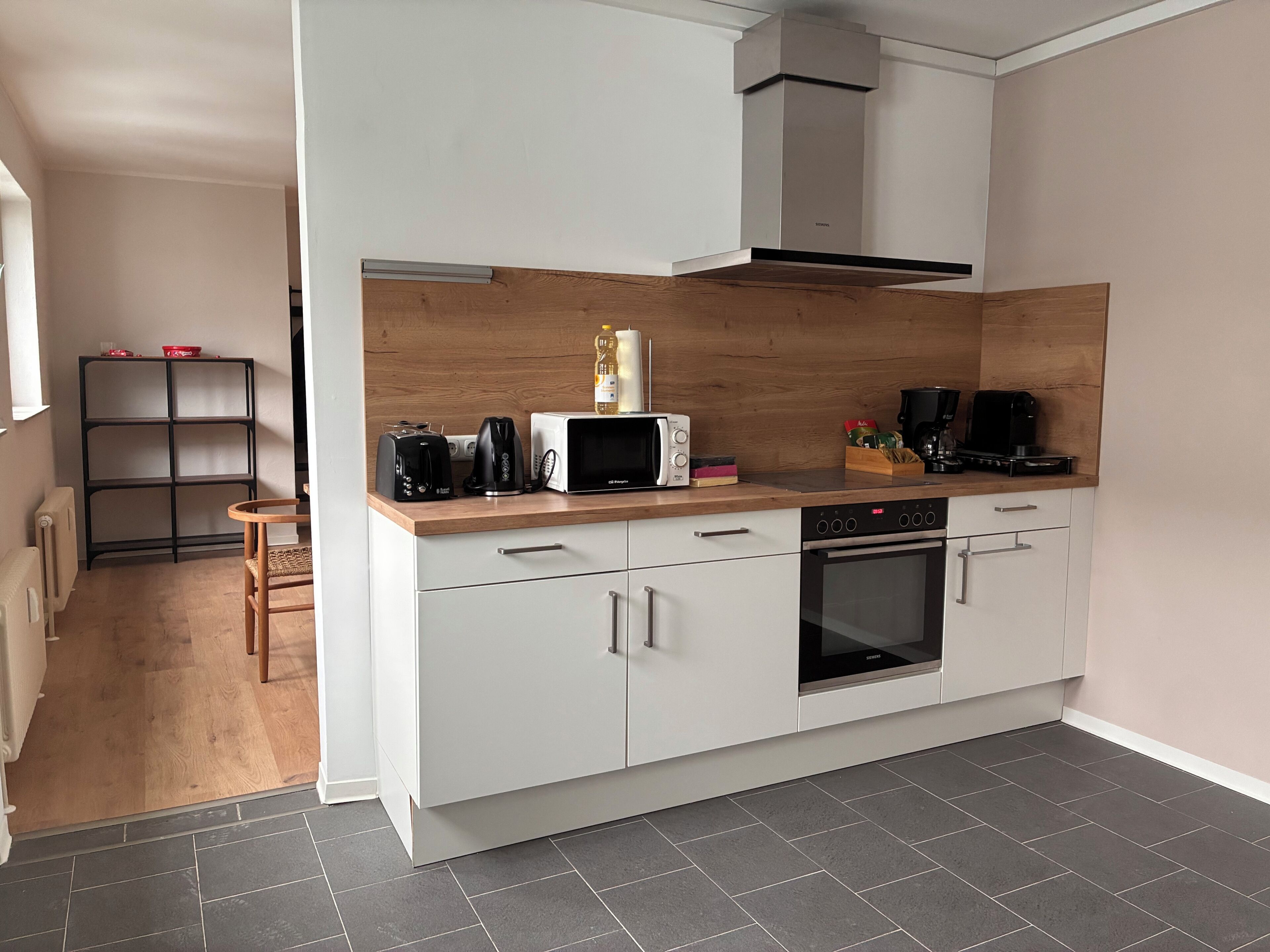 A modern kitchen with a microwave, toaster, kettle, and coffee maker on the countertop.