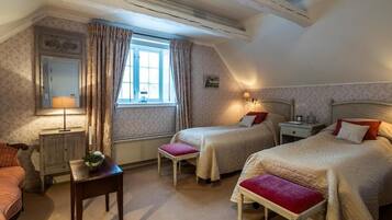 Un dormitorio con dos camas, una mesita de noche, un aparador, una ventana con cortinas y una lámpara.
