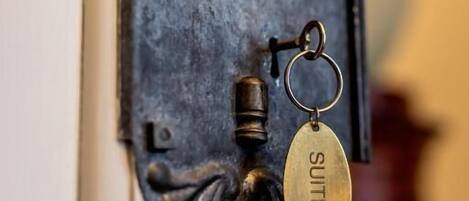 A brass door knocker with a keychain attached, mounted on a white door.