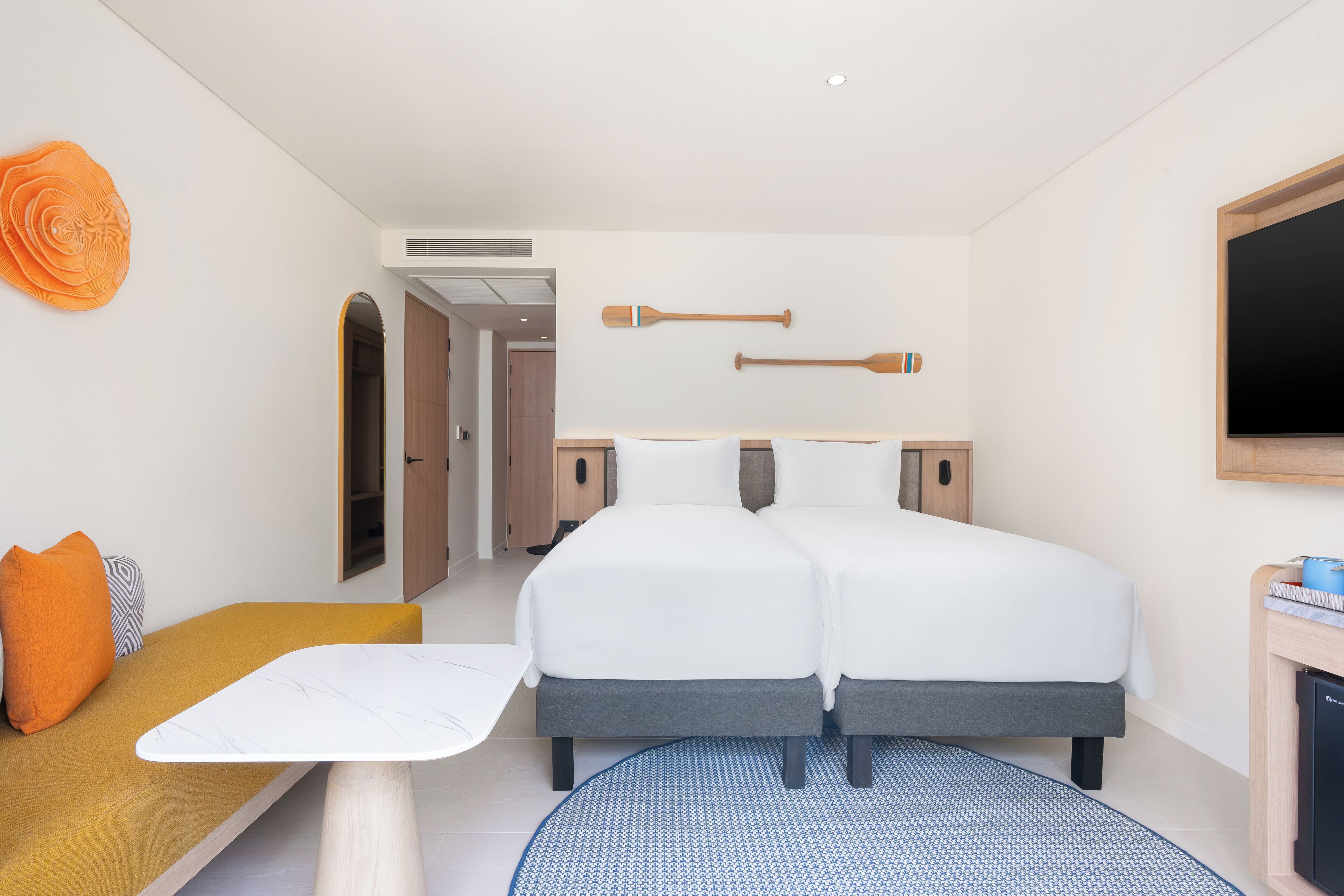 A hotel room with a double bed, a small table, a sofa, and a TV.