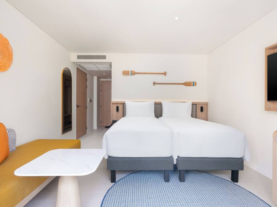 Een hotelkamer met een tweepersoonsbed, een tafeltje, een bank en een televisie.