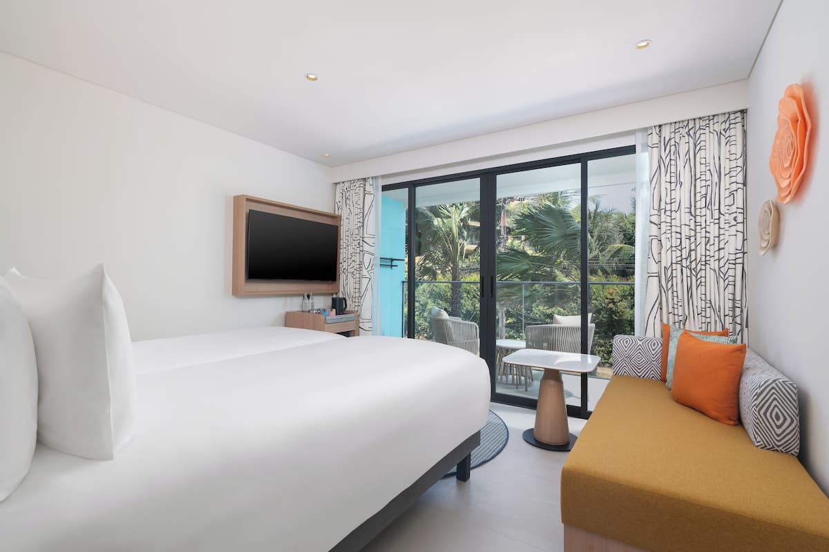 Une chambre d’hôtel moderne dotée d’un grand lit, d’un canapé, d’une télévision et d’un balcon aménagé avec du mobilier d’extérieur.