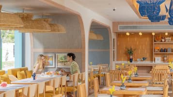 A restaurant with wooden tables and chairs, hanging wicker lamps, and a view of the outdoors.