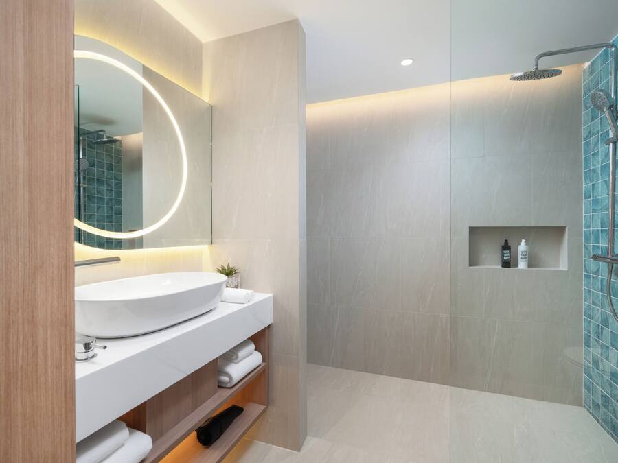 A modern bathroom with a large sink, mirror, and shower.