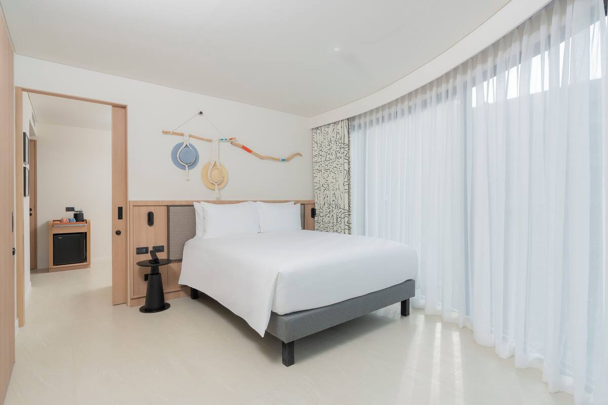 Une chambre d’hôtel moderne avec un grand lit, un petit bureau et une armoire.