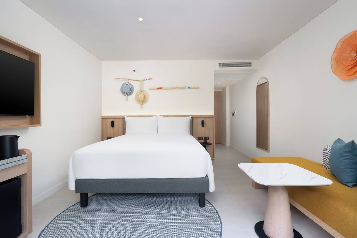 Une chambre d’hôtel moderne avec un grand lit, un bureau et une télévision.