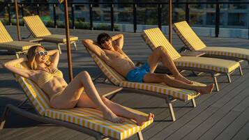 A poolside area with striped lounge chairs and a wooden deck.