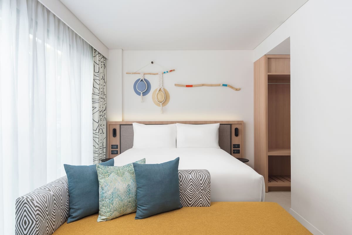 Une chambre d’hôtel moderne avec un lit bien fait, une table de chevet et une armoire.