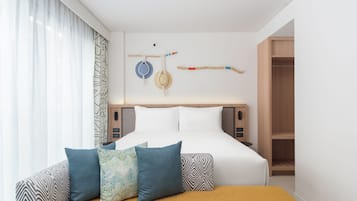 A modern hotel room with a neatly made bed, a bedside table, and a wardrobe.
