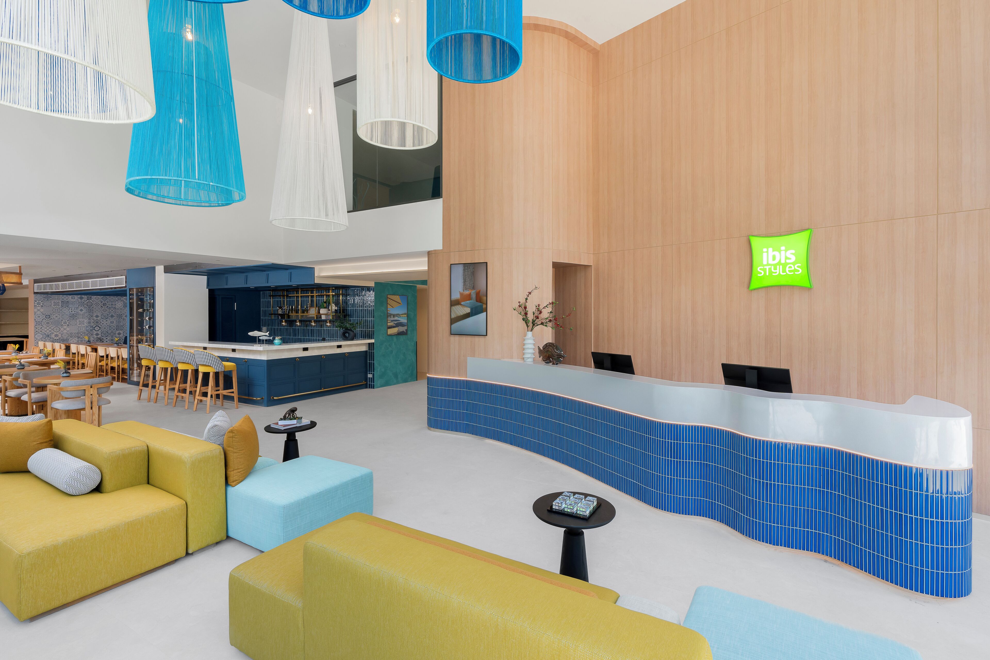 Un moderno vestíbulo de hotel con mostrador de recepción, zona de estar y bar.
