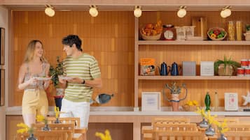 Interior de un restaurante con paneles de madera, una barra con distintos alimentos y una zona de estar con mesas y sillas.