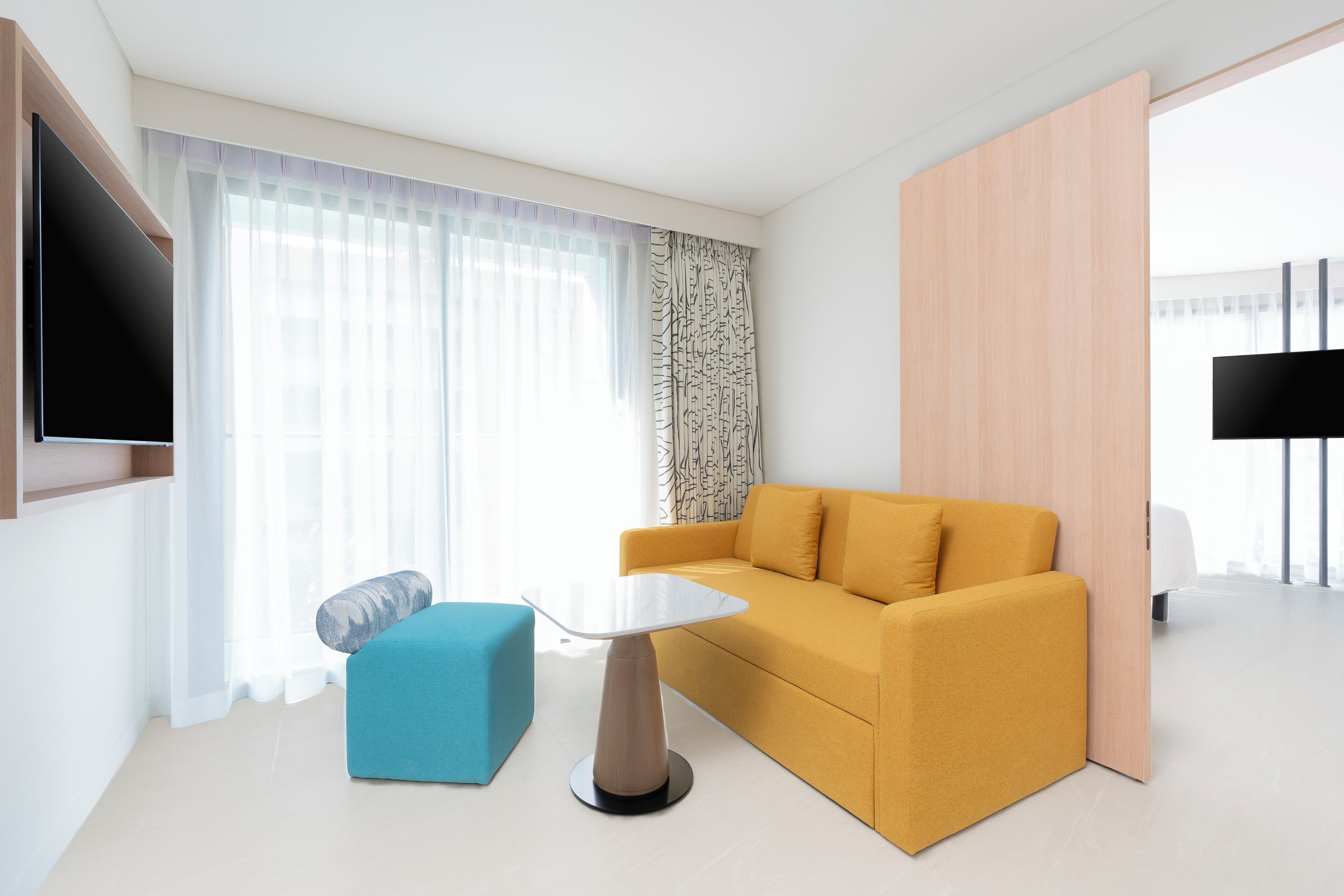 A modern living room with a sofa, a small table, and a TV mounted on the wall.