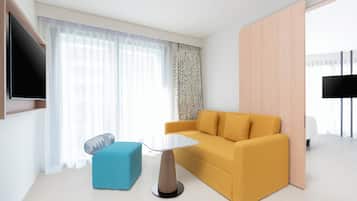 A modern living room with a sofa, a small table, and a TV mounted on the wall.