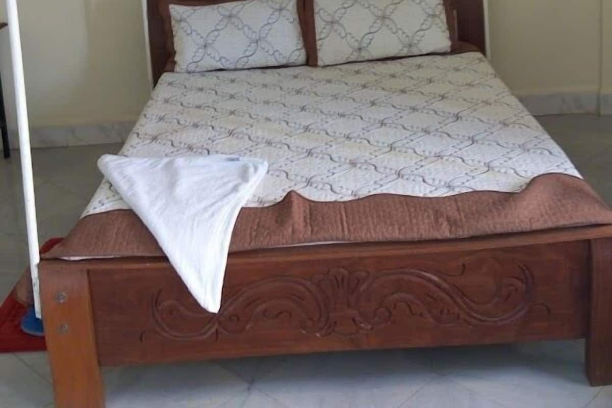 A bed with a canopy, a wooden headboard, and patterned bedding.