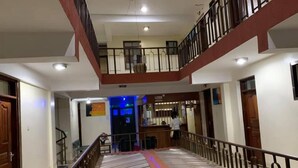 A multi-level hotel lobby with a central staircase, wooden doors, and a reception desk. - Market View Hotel Taveta (Taveta)