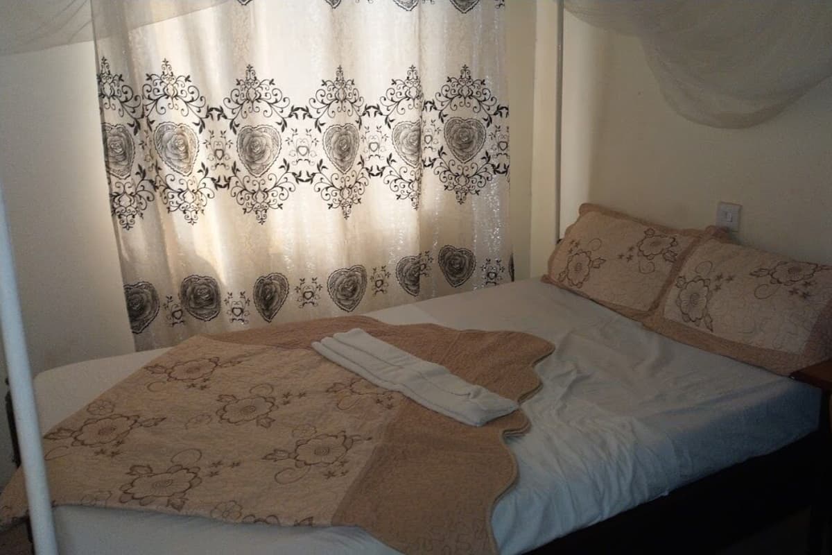 A bedroom with a bed, a blanket, and a pillow.