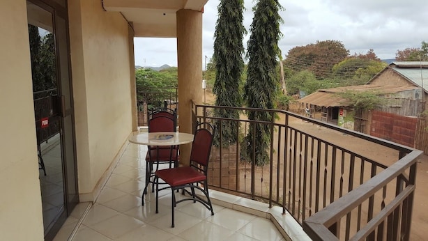 A balcony with a table and chairs, a view of the surrounding area, and a railing. - Market View Hotel Taveta (Taveta)